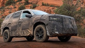 A camoflauge-wrapped 2023 Honda Pilot against trees.