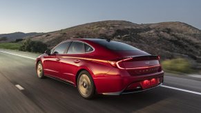 A red 2023 Hyundai Sonata Hybrid driving in the opposite direction