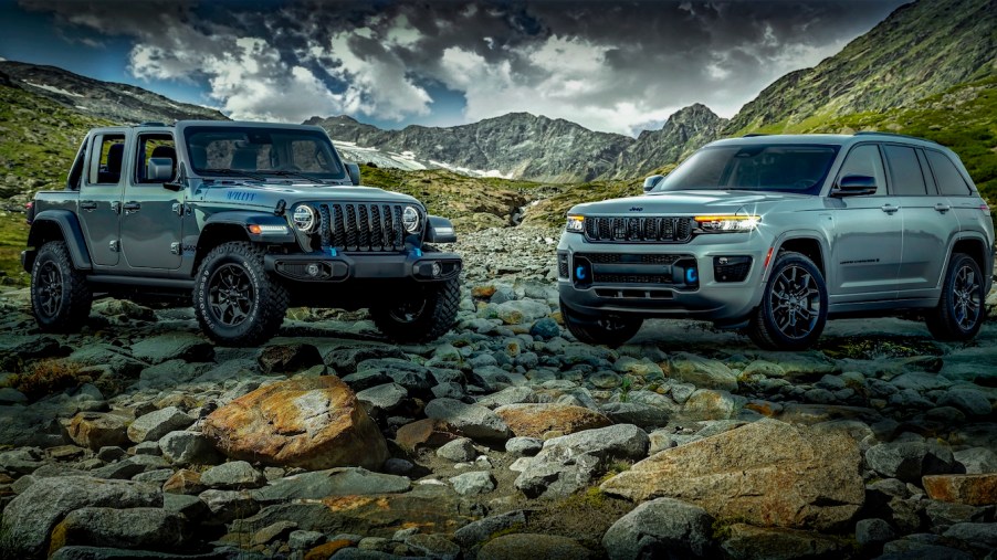 Two gray Jeep plug-in hybrid SUVs parked in a valley for a promo shot, mountains and clouds visible in the background.