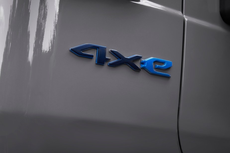 Detail shot of a Jeep 4xe logo, the gray fender of a plug-in hybrid SUV visible in the background.