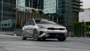 A silver gray 2023 Kia Forte compact sedan model parked on a rooftop in a dense city