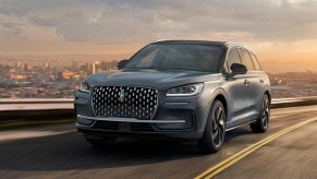 A gray 2023 Lincoln Corsair small luxury SUV is driving on the road.
