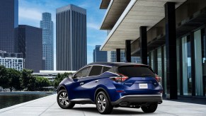 A blue Nissan Murano parked in front of a city skyline.