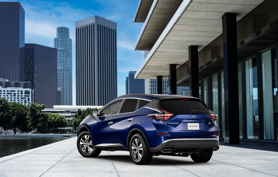 A blue Nissan Murano parked in front of a city skyline. 