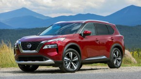 A red 2023 Nissan Rogue Sport parked in front of a mountainous landscape.
