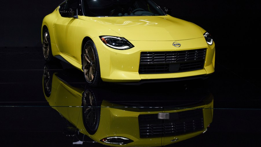 A yellow 2023 Nissan Z parked in a dark lit black room.