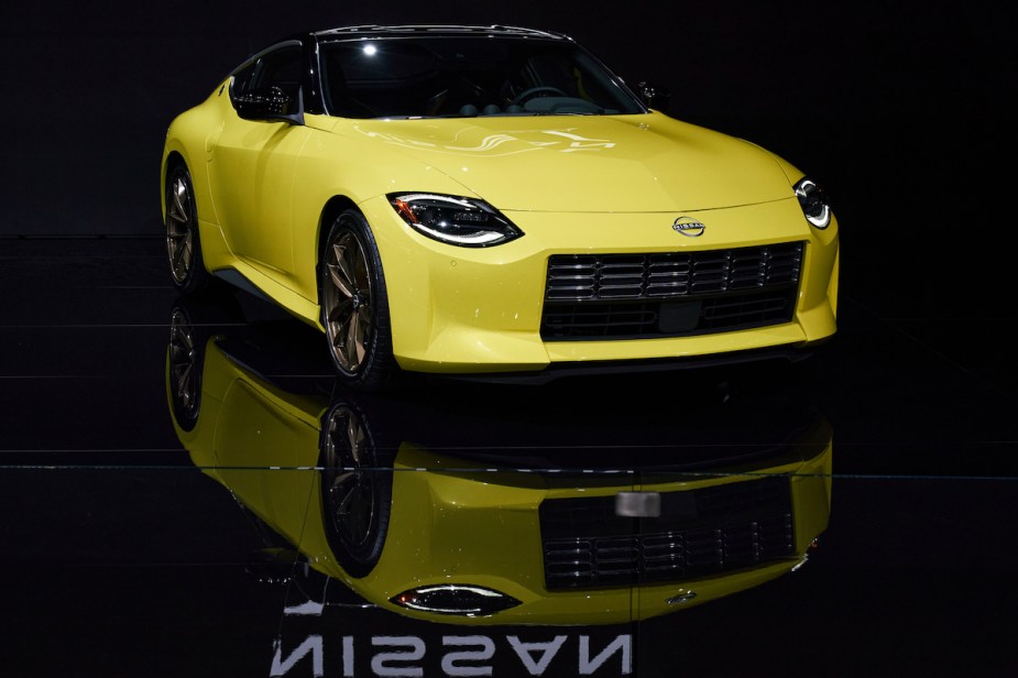 A yellow 2023 Nissan Z parked in a dark lit black room. 