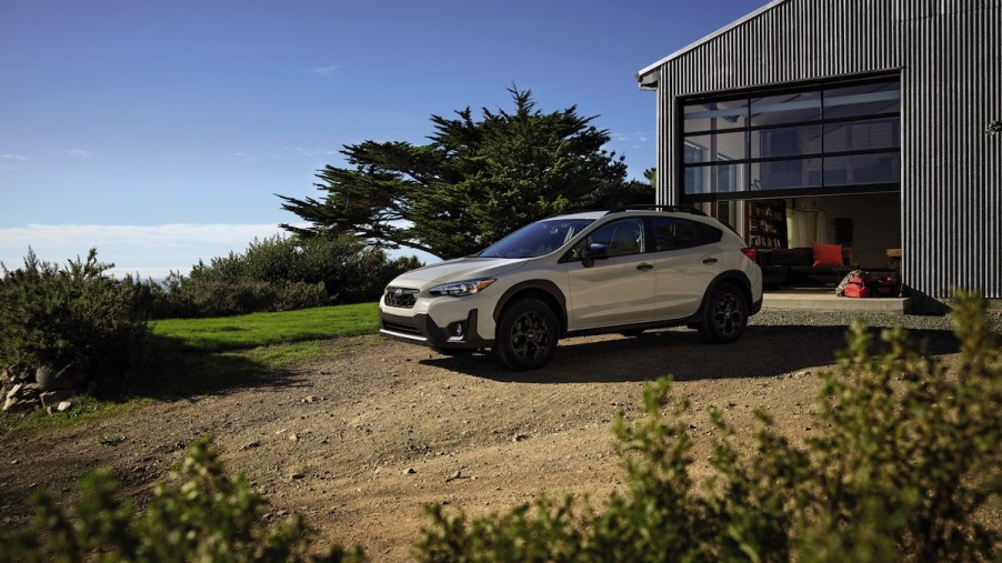 A 2023 Subaru Crosstrek parked in a dirt area in front of a barn-like building.
