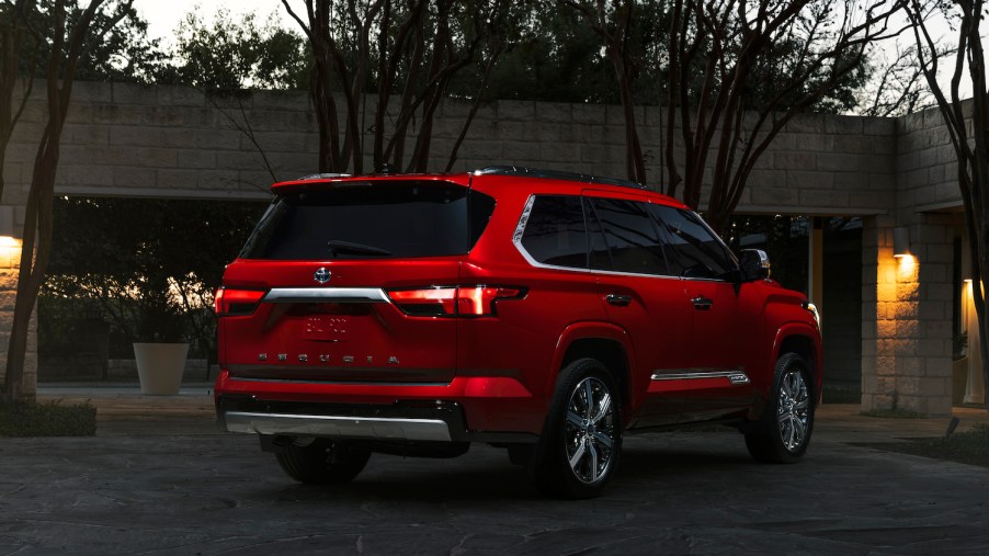 Red 2023 Toyota Sequoia SUV parked in a driveway, a house visible in the background.