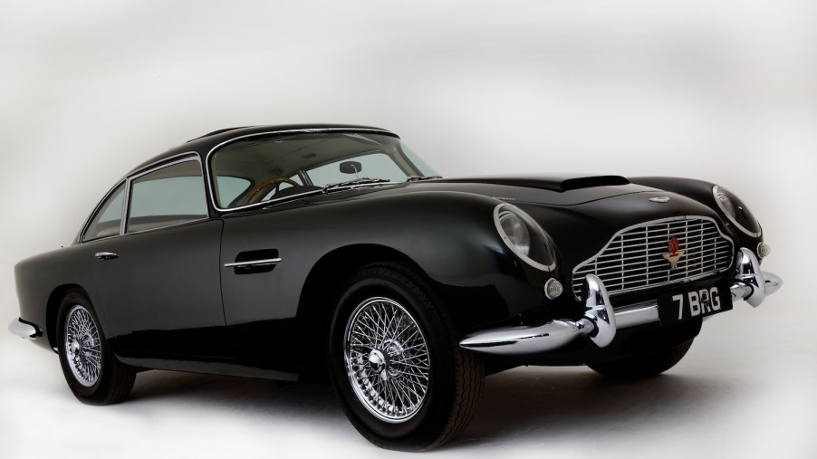 Black Aston Martin DB4 GT sports car parked in front of a white backdrop.