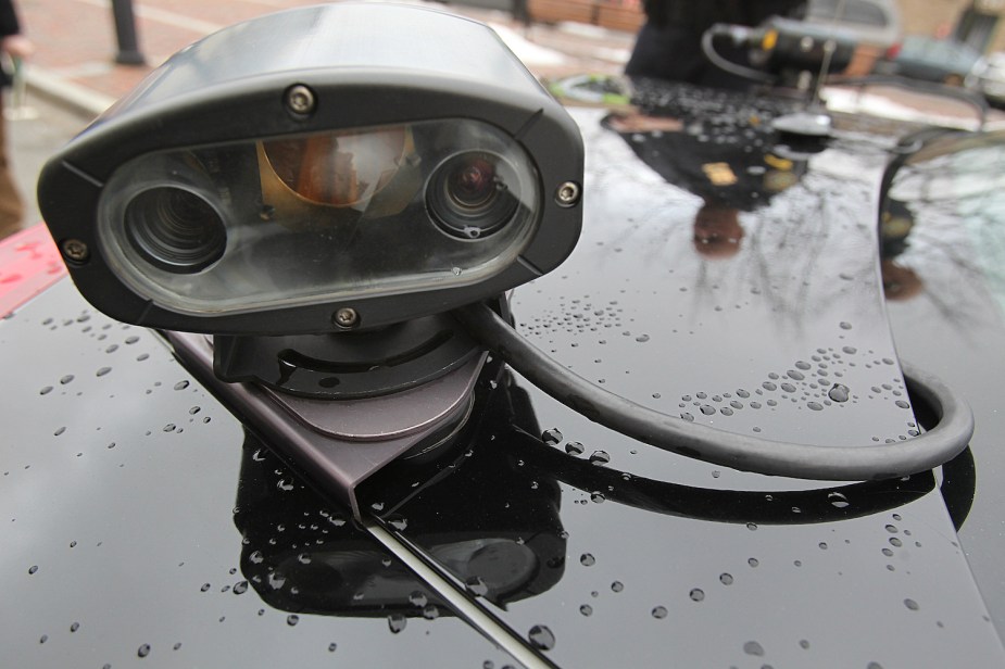Closeup of the license plate scanner mounted on the trunk of a police cruiser in Boston massachusetts, rain drops visible on the metal surface.
