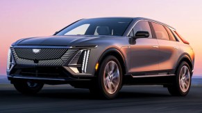 A gray 2023 Cadillac Lyriq midsize electric SUV is driving on the road.