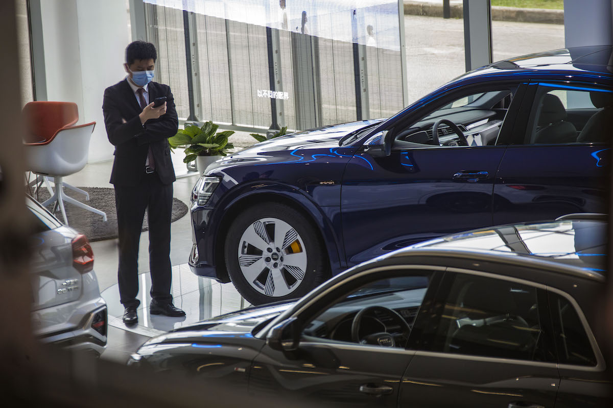 A person potentially preparing to buy an expensive luxury car at an Audi dealership.