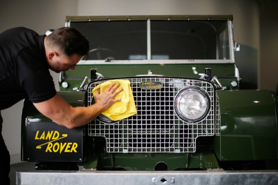 An employee cleans the headlights of Land Rover Series One