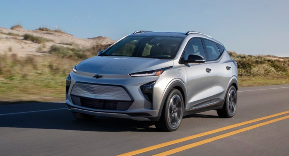 A gray Chevy Bolt EUV subcompact electric SUV is driving on the road.