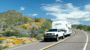 A Chevy truck towing a 5th wheel camper RV on North Lake Road near the Tonto National Forest in Arizona