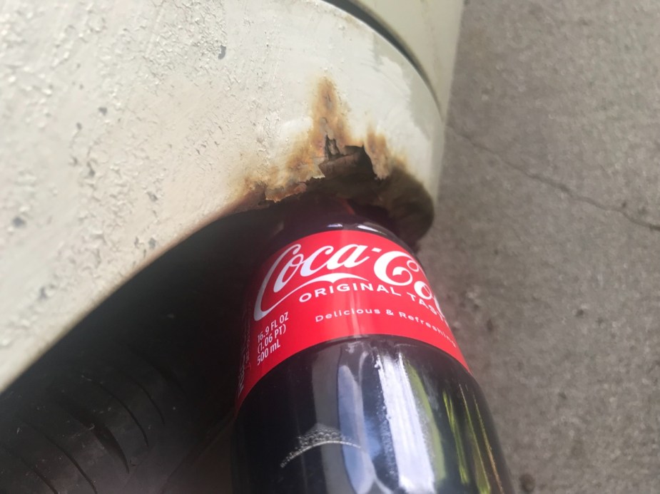 Coca-Cola poured on rust spot, highlighting how Coke can remove rust from car
