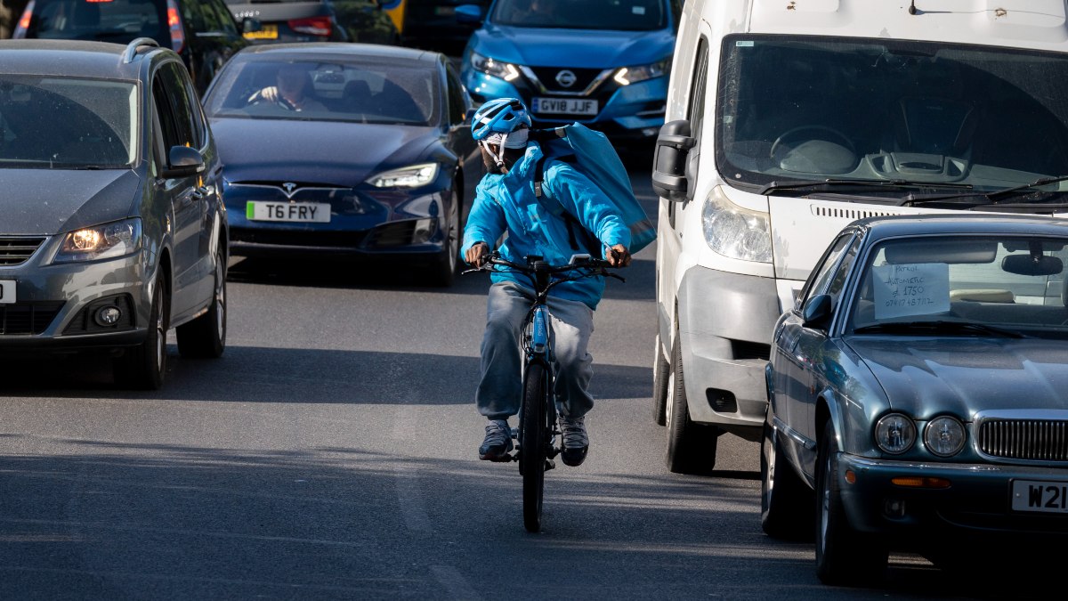 Cyclist riding in heavy traffic, highlighting whether bikes or cars cause mor accidents