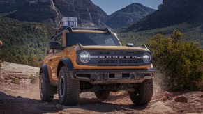A yellow Ford Bronco midsize SUV is driving off-road.