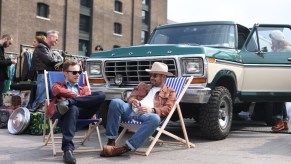 An old Ford truck sits in a parking lot, it might have dual fuel tanks.