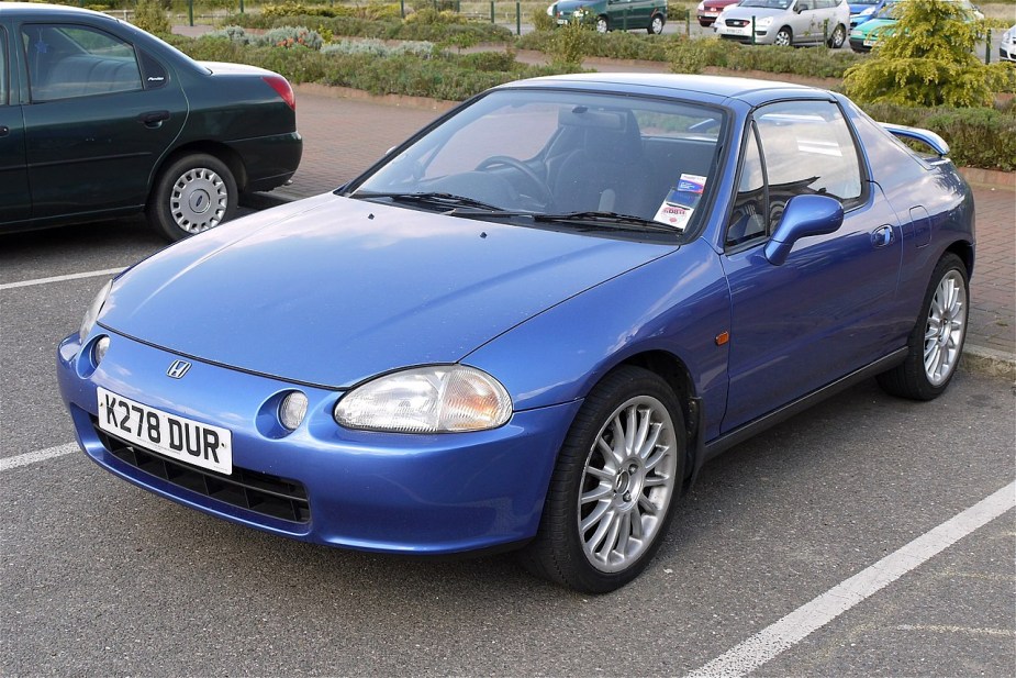 A blue Honda Del Sol sits in a parking spot