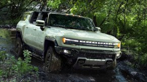 A green GMC Hummer EV is driving off-road.