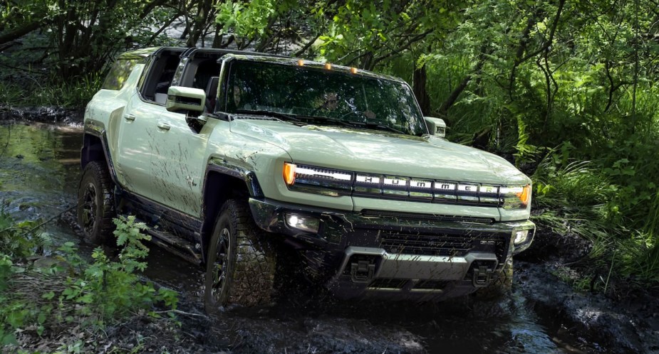 A green GMC Hummer EV is driving off-road. 