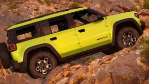 A green Jeep Recon fully-electric small SUV is driving up the hill.