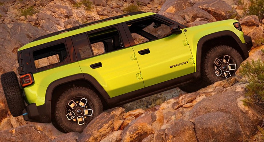 A green 2024 Jeep Recon EV electric SUV is driving up a hill. 