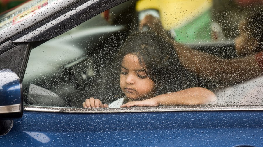A kid in a car looking out the window.