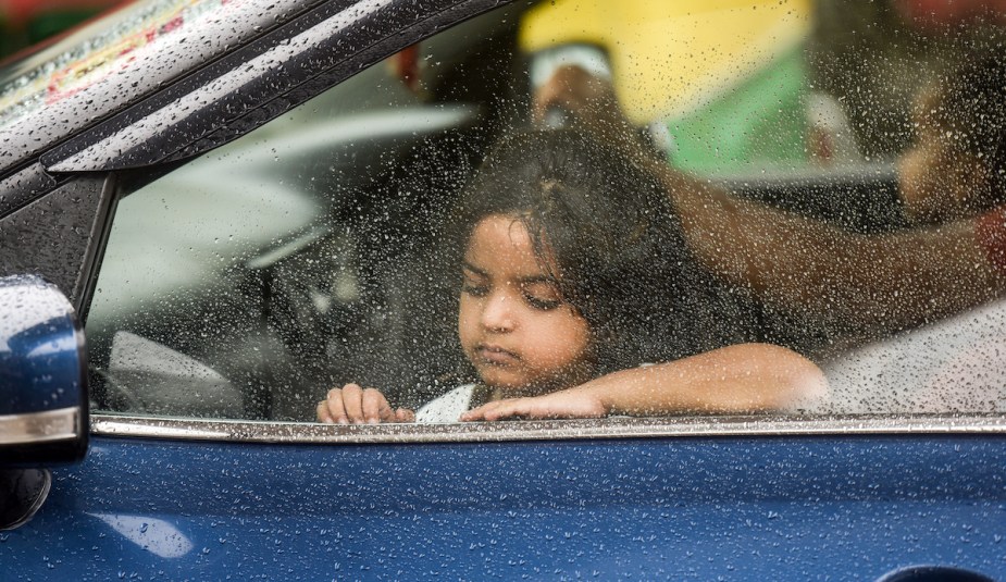 A kid in a car looking out the window. 
