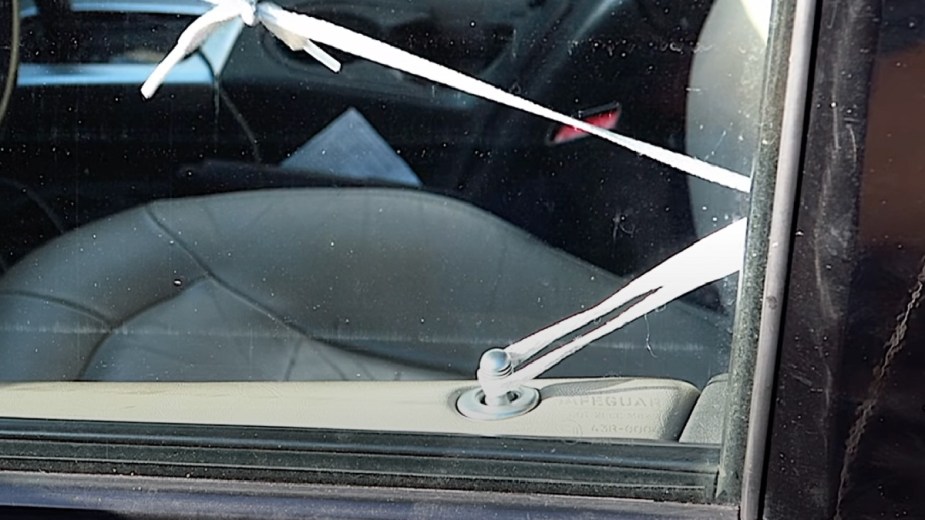Man using a shoelace string to unlock a car door of an SUV