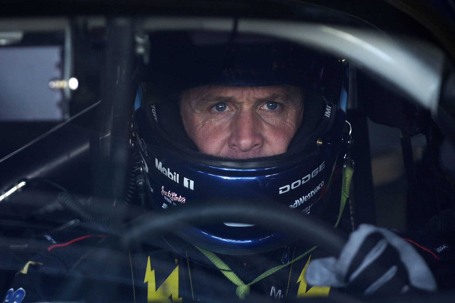 NASCAR driver Rusty Wallace is behind the wheel of a race car with his helmet.