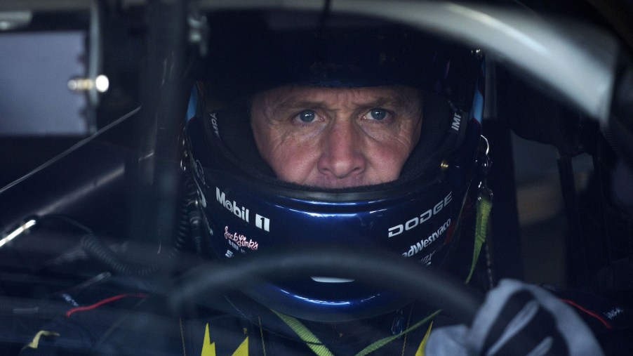 NASCAR driver Rusty Wallace behind the wheel of his race car with his helmet on.
