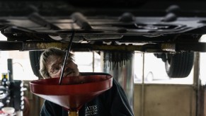 A mechanic is watching the oil spill from an oil pan