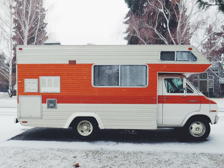 A red and white RV is parked outside with snow on the ground.