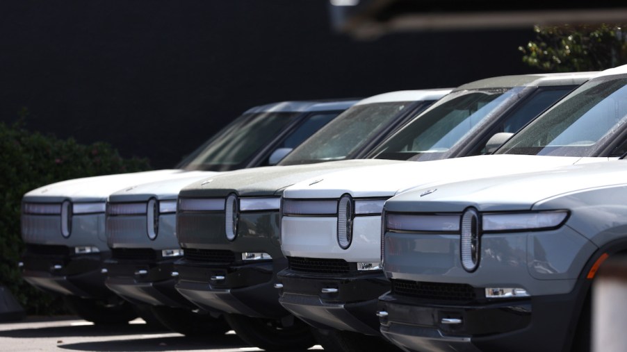 The front of several Rivian R1T trucks in a row.