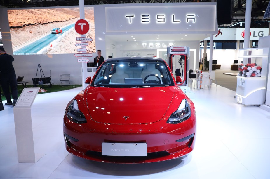 A red Tesla Model 3 parked indoors.