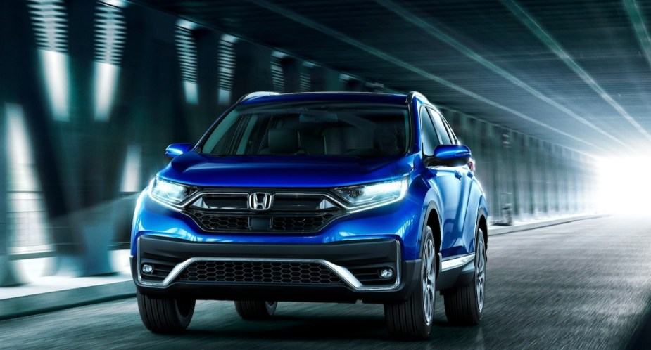 A blue Honda CR-V small SUV drives on the road.