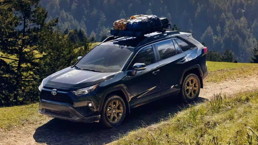 A blue 2022 Toyota RAV4 Hybrid Woodland Edition is driving off-road.