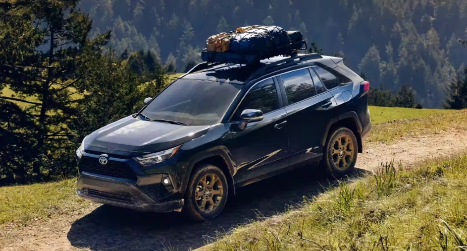 A blue Toyota RAV4 Hybrid Woodland Edition is driving off-road. 