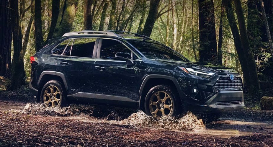 A blue 2023 Toyota RAV4 Hybrid Woodland Edition is driving off-road. 