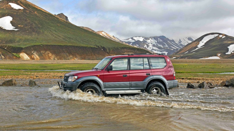 An 80-Series Toyota Land Cruiser fords a small body of water.