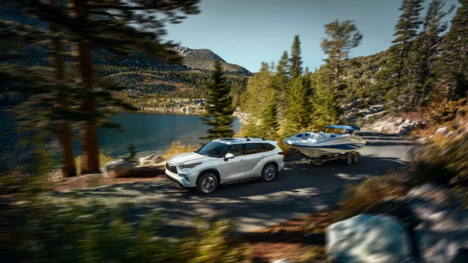 White 2023 Toyota Highlander SUV towing a boat