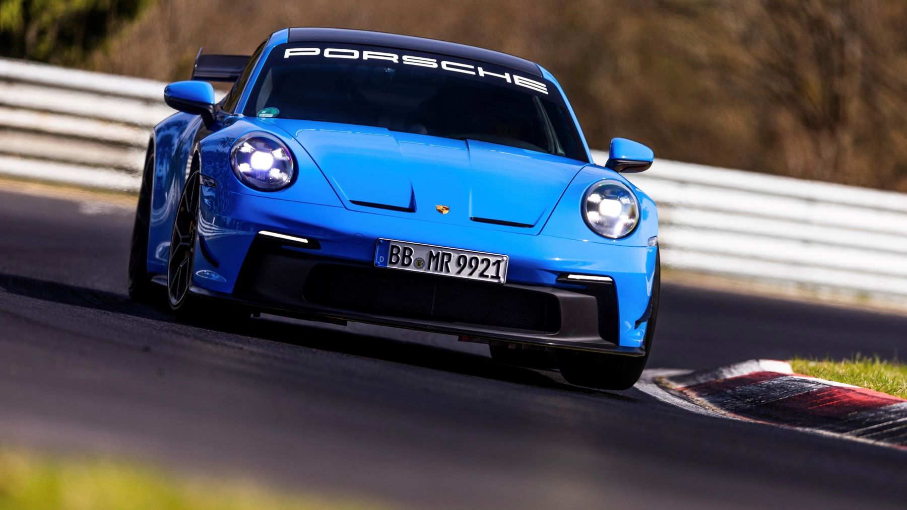 A light blue 2022 Porsche 911 GT3 performance sports car with available AWD driving on a racetrack