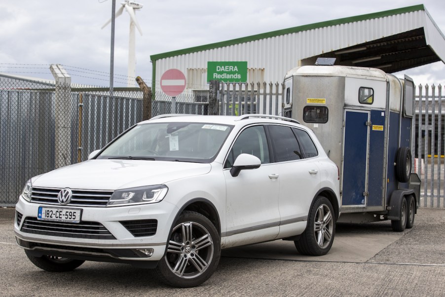 A white car towing a trailer.