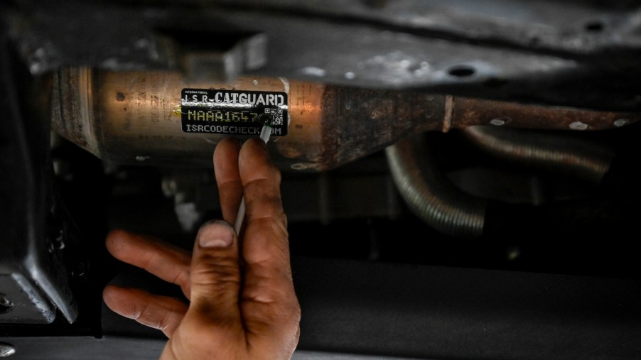 A mechanic places a sticker on the catalytic converter of a Toyota Tacoma.