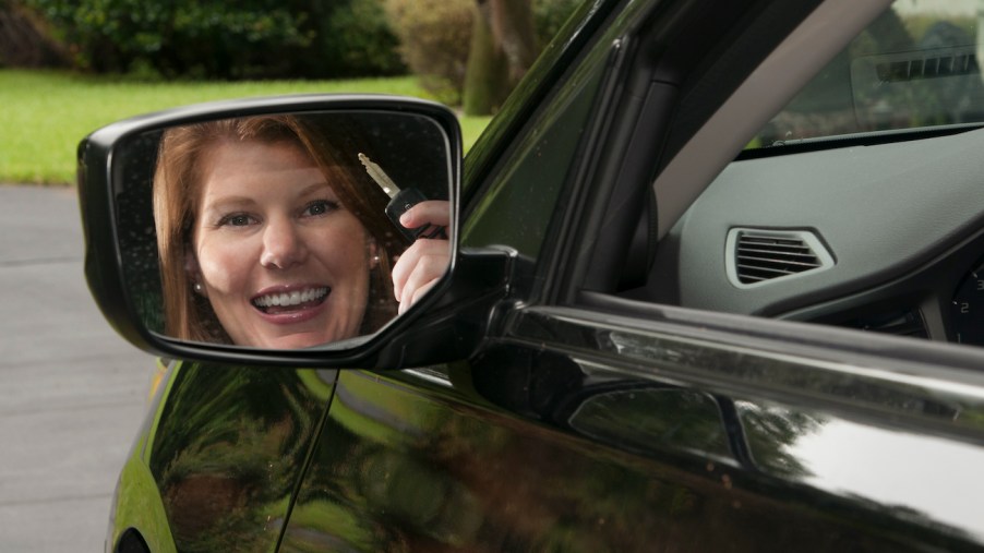 A happy driver holds up her car key.