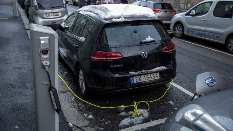Electric cars, including a VW e-Golf, covered in snow, plugged into public charging stations in Oslo, Norway