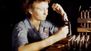 A female service worker reconditioning spark plugs at a Navy Air Base